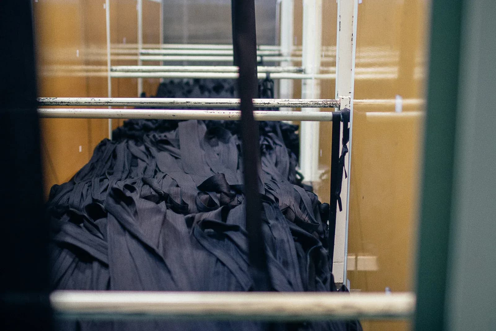 Skeins of indigo-dyed yarn heaped on a rack in the dye house at Kuroki Mills, against an ochre wall