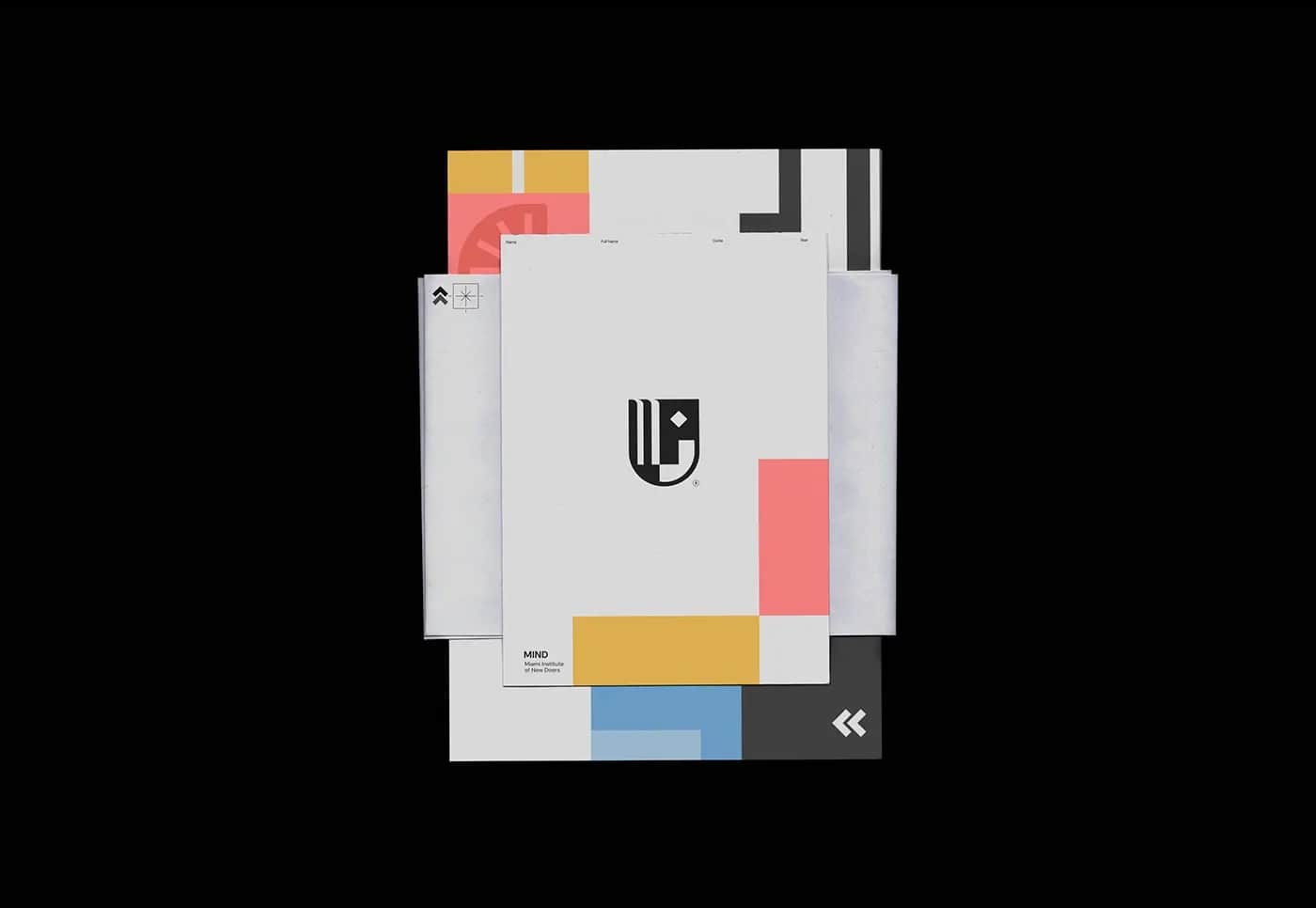 Overhead view of letterhead and colour-blocked sheets in coral, yellow and blue, fanned across a black surface.