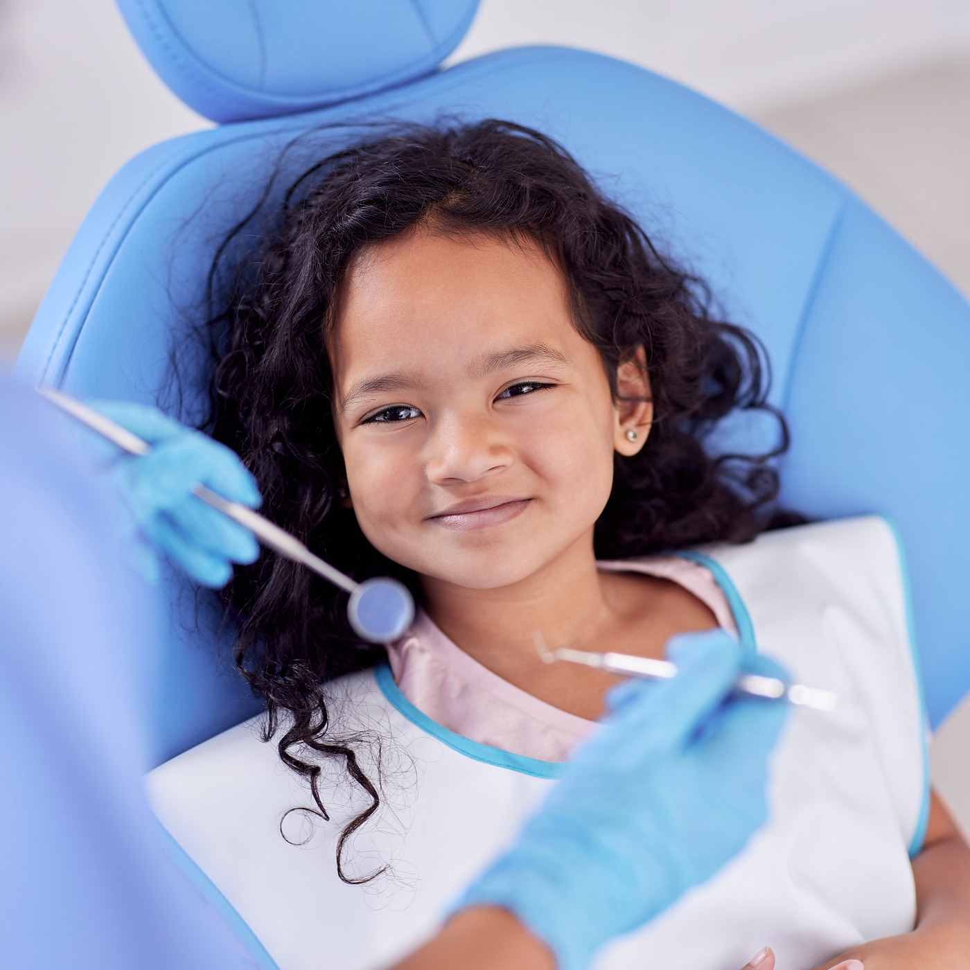 A young girl smiling in the dental chair at a checkup.