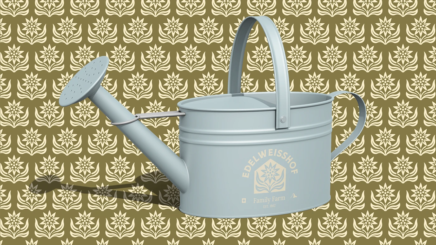 A pale blue enamel Edelweisshof watering can, crest printed on its side, photographed against the moss-and-bone edelweiss pattern