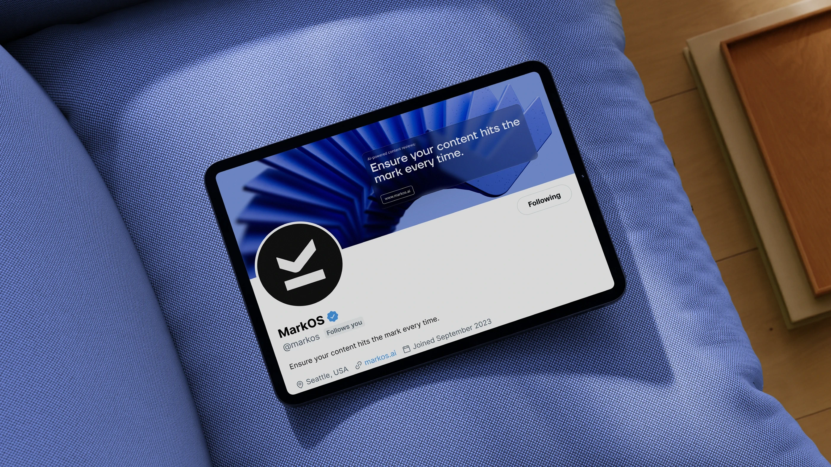 The Mark OS profile on X viewed on a tablet, with the sculpted blue banner and circular logomark avatar