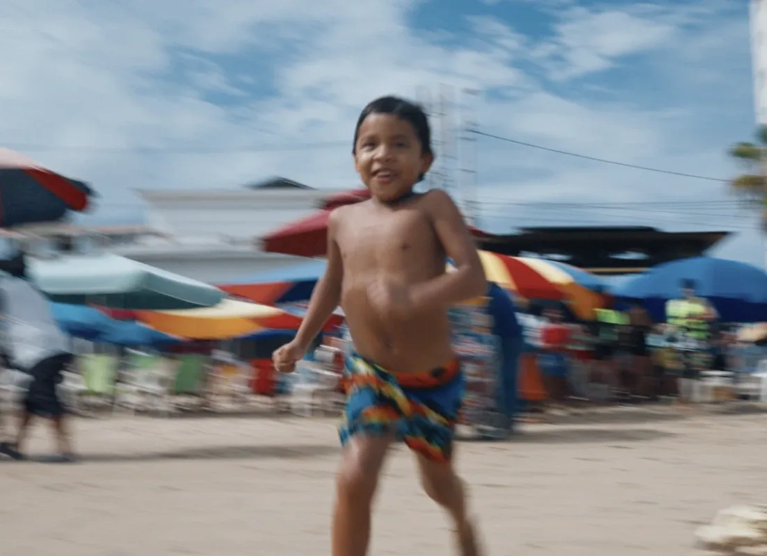 A child running along the sand past rows of beach umbrellas at Manta