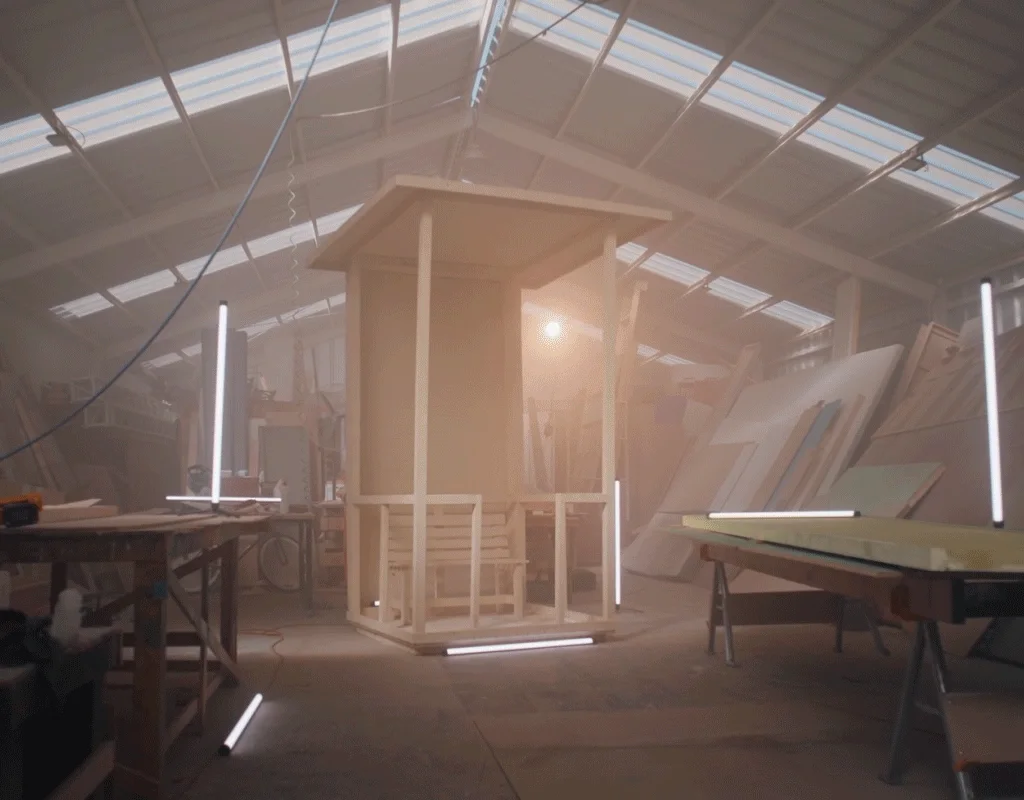 A Safety Ads lifeguard tower under construction in a daylit workshop, its timber frame standing between work benches