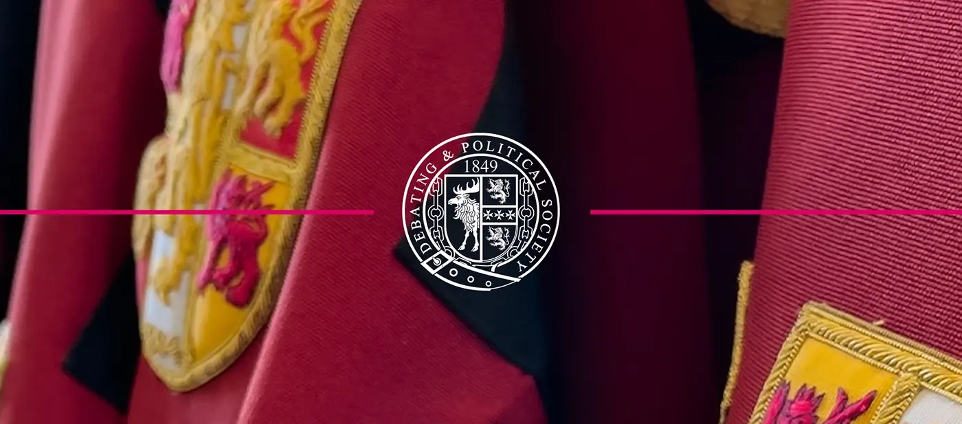 Close-up of crimson ceremonial robes with gold bullion embroidery, overlaid with a circular debating society crest.