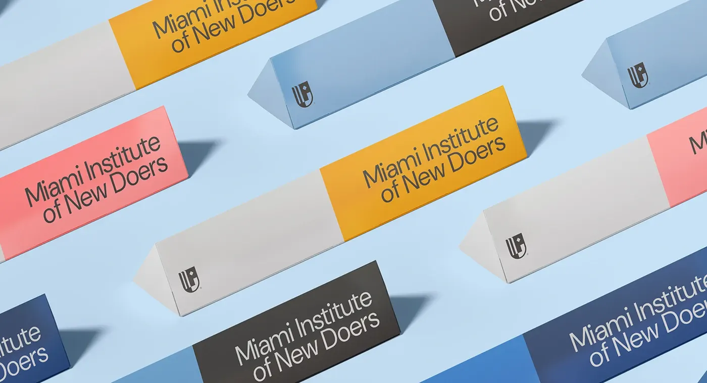 An array of triangular table signs and flat cards in the identity palette of coral, marigold, grey and blue on a pale blue backdrop.
