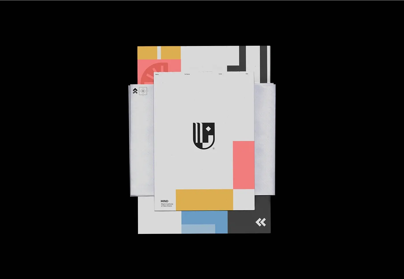 Overhead view of letterhead and colour-blocked sheets in coral, yellow and blue, fanned across a black surface.